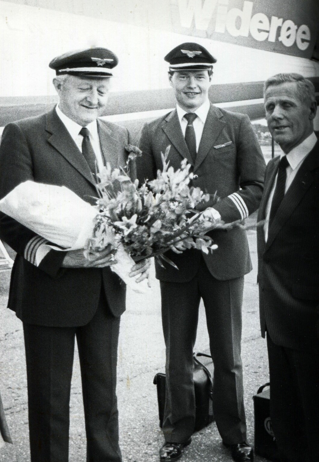 En lang flygerkarriere var over 25. april 1986. Erik Langset med sønnen Jon som styrmann, overrekkes blomster av Widerøes direktør Peter L. Nissen etter landing. Foto: Via Ulf Larstuvold. En lang flygerkarriere var over 25. april 1986. Erik Langset med sønnen Jon som styrmann, overrekkes blomster av Widerøes direktør Peter L. Nissen etter landing. Foto: Via Ulf Larstuvold.